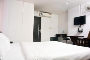 a bedroom with a white bed and a desk at MALAPPURAM RESIDENCY in Malappuram