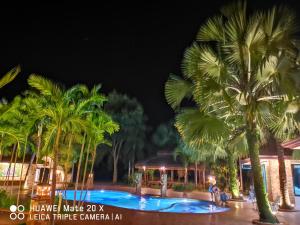 坤敬RS Phong Riverside Resort的棕榈树的夜间度假村游泳池