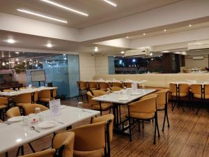 a dining room with white tables and chairs at Nasiklub in Nashik