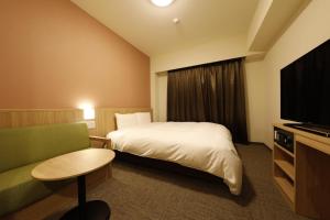 a hotel room with a bed and a television at Dormy Inn Mito in Mito