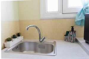 a stainless steel sink in a kitchen with yellow tiles at Tropical Loft with View in Volos