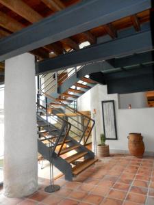 uma escada em espiral metálica num quarto com piso em tijolo em El Turcal em Torremenga