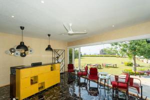 a living room with red chairs and a yellow cabinet at The G Snoozebox in Udaipur