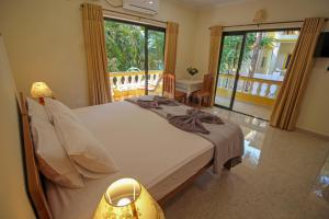 a bedroom with a large bed and a balcony at Primavera Holiday Homes in Candolim