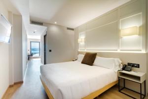 a bedroom with a white bed and a phone on a table at Playa de Foz Hotel & Spa by gaiarooms in Foz +53 photos