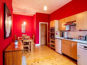 uma cozinha com paredes vermelhas e piso em madeira em Pass the Keys Beautiful and Bright Georgian Style Morningside Apartment em Edimburgo