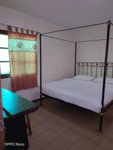 1 dormitorio con cama con dosel y mesa en Kuching Waterfront Lodge, en Kuching