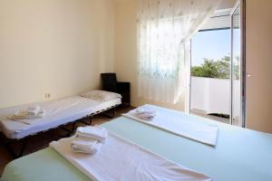 two beds in a room with a large window at Apartments Matin in Novalja