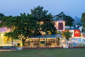 a restaurant with tables and a tree next to a pool at The G Snoozebox in Udaipur