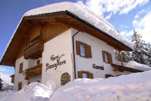 un edificio cubierto de nieve con nieve alrededor en Garni Biancaneve Ruffrè-Mendola en Mendola