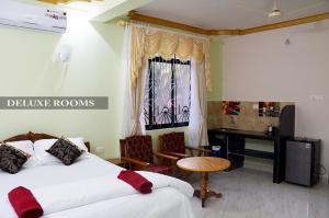 a hotel room with two beds and a desk at Pritams Cottages Guest House in Palolem