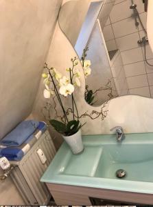 a bathroom with a vase with flowers on a sink at Die Altstadt Appartements Caprice in Goslar