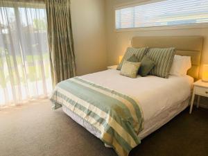 ein Schlafzimmer mit einem Bett mit Kissen und einem Fenster in der Unterkunft Hawke's Bay Haven in Napier