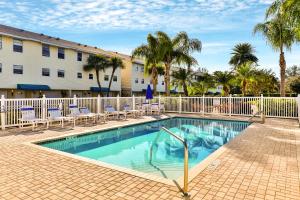 a swimming pool in front of a hotel with palm trees at Captain Coves #102 in Clearwater Beach