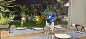 a table with chairs and a playground in the background at Meritas Adore Resort in Lonavala
