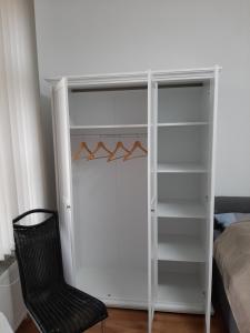 a white closet with a black chair next to a bed at Ferienwohnung Zum Rapunzelturm in Schwedt