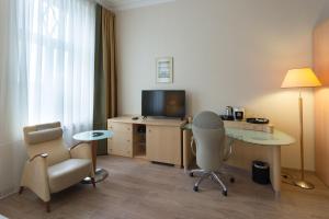 a hotel room with a desk and a chair and a television at Brass Suites in Łódź