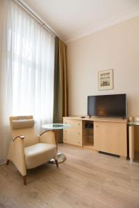 a living room with a chair and a television at Brass Suites in Łódź