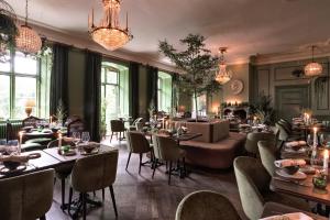 a restaurant with tables and chairs and a chandelier at Åkeshofs Slott in Stockholm