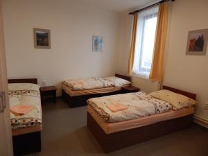 three beds in a room with a window at Penzion U Kašných in Mníšek pod Brdy