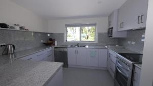 a large kitchen with white cabinets and a window at Umtali Beach House in Bridport