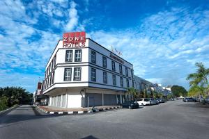 Un bâtiment blanc avec un panneau en haut dans l'établissement ZONE Hotels, Telok Panglima Garang, à Teluk Panglima Garang