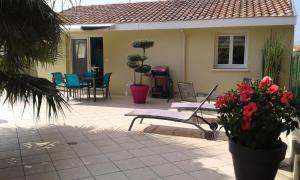 una casa con un patio con sillas y flores en T2 Tarnos avec piscine en Labenne