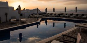 a hotel swimming pool with chairs and umbrellas at Agnadi View Villa in Oia