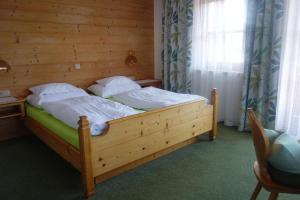 Cama grande de madera en habitación con ventana en Haus Postfeld en Alpbach