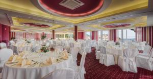 um salão de banquetes com mesas e cadeiras brancas em Hotel Zora em Primošten