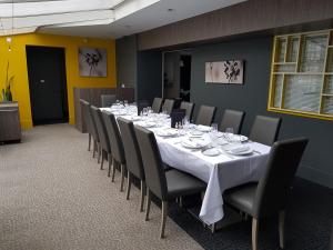 a long dining room with a long table and chairs at Logis Hôtel A la Bonne Auberge in Laval