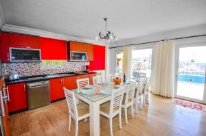 una cucina con armadi rossi e un tavolo con sedie di Villa Alkin a Kalkan