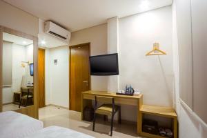 Habitación de hotel con escritorio y TV. en Cordela Inn Bengkulu en Bengkulu