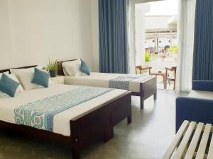 a hotel room with two beds and a balcony at Hotel Blue Note in Hikkaduwa