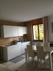 マルチェージネにあるVilla Arianna Panoramic Apartmentsの白いキャビネット、テーブルと椅子付きのキッチンが備わります。