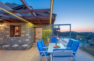 a patio with blue chairs and a table with a view at Villa Ligaria, Lygaria in Agia Pelagia