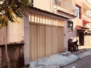 two people sitting on a bench in front of a garage at Buff Hostel Tirana in Tirana