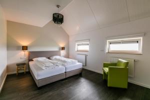 a bedroom with a bed and a green chair at Hofwestdijk in Vrouwenpolder
