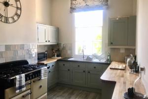 a kitchen with green cabinets and a stove and a window at The Terrace in Cheltenham