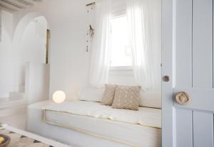 a white living room with a white couch in front of a window at Agnandi Cielo in Tourlos