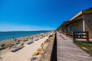 una spiaggia con sedie e un edificio e l'oceano di Golfo del Sole Holiday Resort a Follonica
