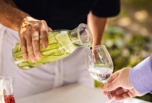 a person pouring a bottle of wine into a glass at ODELYA - Stadthotel im Park in Basel