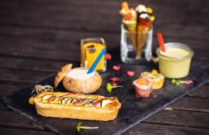 a sandwich on a black plate with a drink and food at ODELYA - Stadthotel im Park in Basel