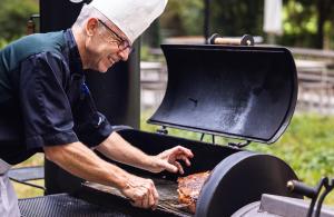 Un uomo sta cucinando cibo su una griglia di ODELYA Hotel & Naturgarten Basel City a Basilea
