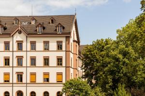 a large white building with a black roof at ODELYA - Stadthotel im Park in Basel