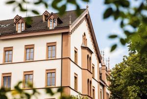 a white building with a gambrel roof at ODELYA - Stadthotel im Park in Basel