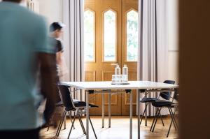 a man standing in front of a table and chairs at ODELYA - Stadthotel im Park in Basel