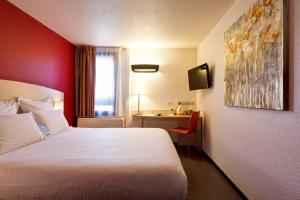 ein Hotelzimmer mit einem weißen Bett und einem Schreibtisch in der Unterkunft Kyriad Lyon Sud - Saint Genis Laval in Saint-Genis-Laval