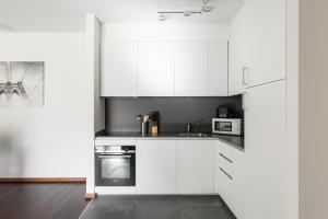 a white kitchen with white cabinets and appliances at Maraini 15 by Quokka 360 - bright flat with lake view in Lugano