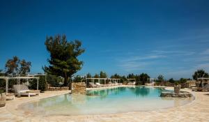 een groot zwembad met stoelen en een boom bij Masseria Montenapoleone in Fasano